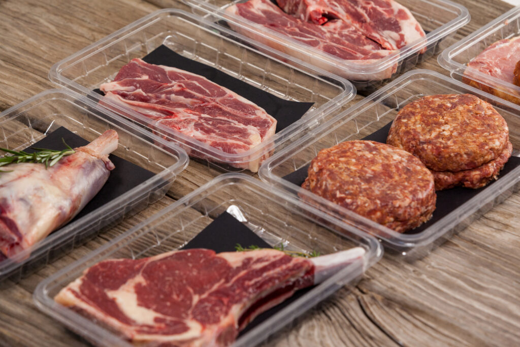 Cuts of raw beef and burger patties in sealed plastic retail trays