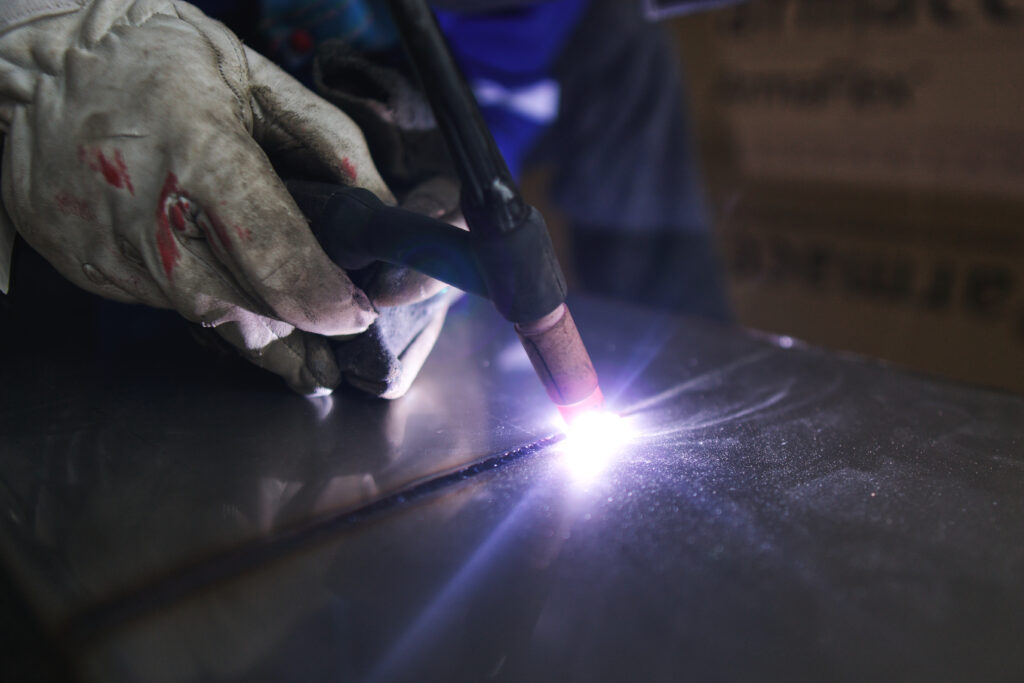 TIG torch with ceramic cup laying a weld bead on stainless steel plate under argon shielding gas