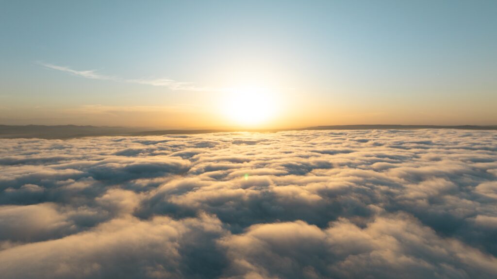 Sun setting above a blanket of clouds seen from high altitude, evoking Earth's atmosphere where krypton is found