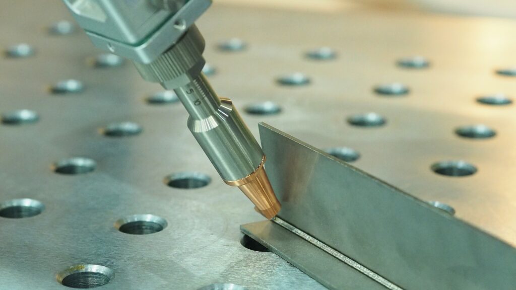 Close-up of a laser welding head joining thin sheet metal along a precision seam